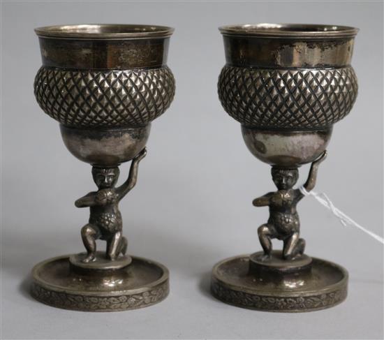A pair of continental white metal goblets with Bacchus figural stems, 10.5cm.